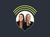 Two female podcast hosts in suits, smiling.