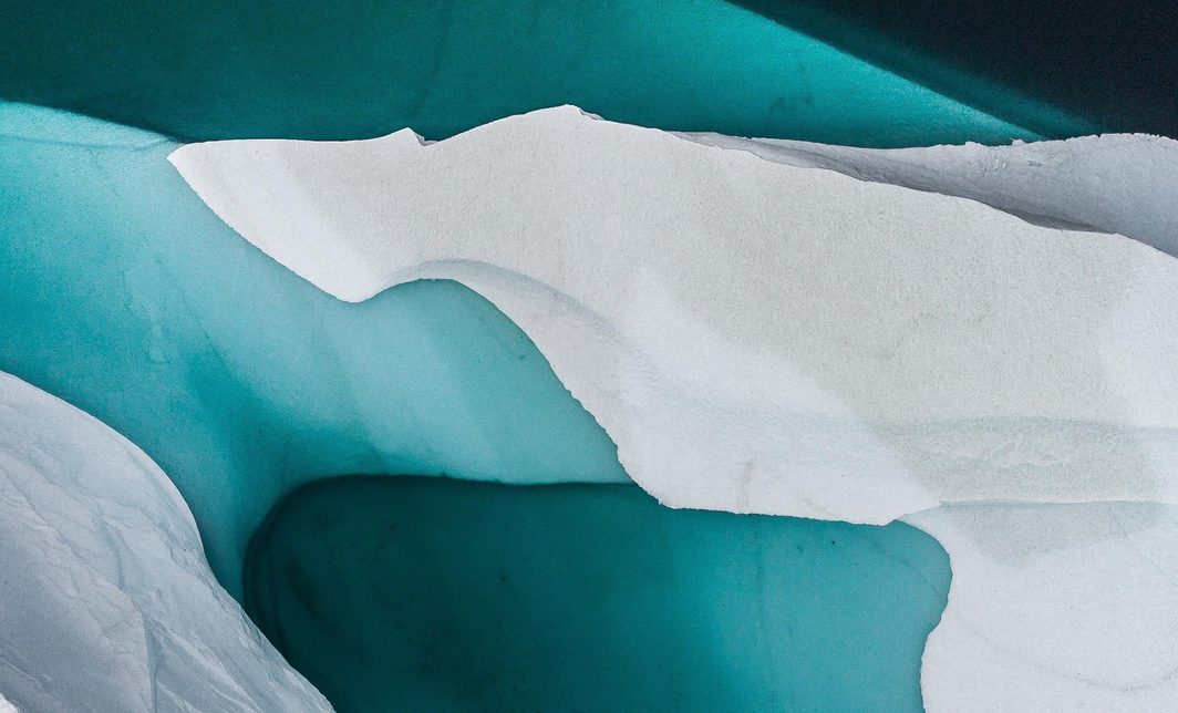 A bright white iceberg, half submerged in turquoise waters.